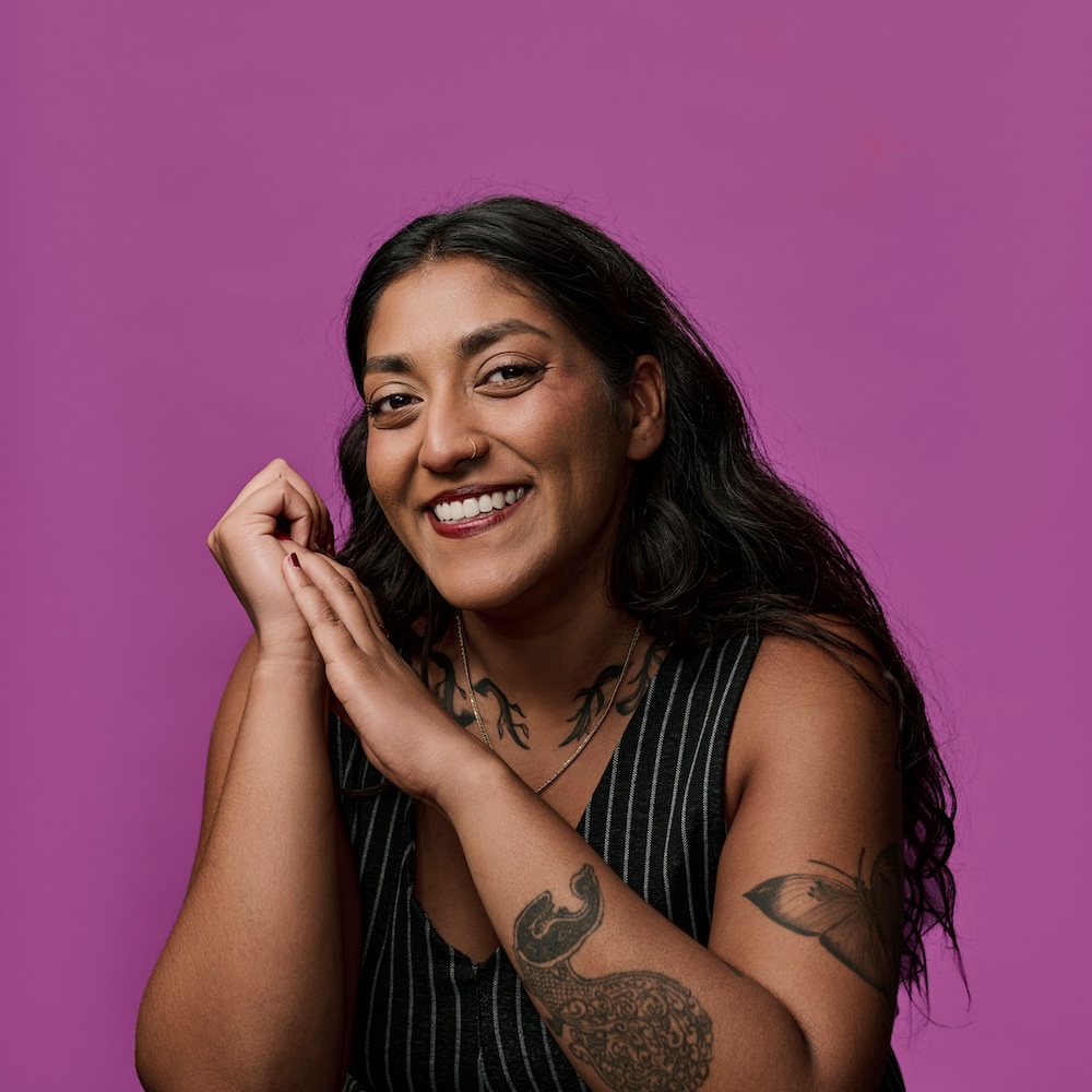 Headshot of Amanda Lowe Warnakulasuriya. She smiles against a bright fuchsia background. 