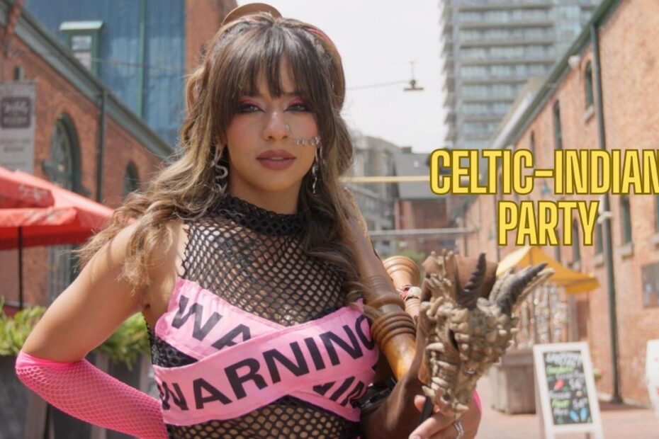 A woman with long wavy hair and bold makeup poses outdoors on a brick street. She wears a black fishnet top crossed with pink "WARNING" tape, holds the chanter of a bagpipe decorated with a small dragon head, and yellow text to the right reads "CELTIC-INDIAN PARTY."